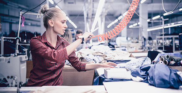 Young Textile Worker Blowing the Stitching Threads from Materials
